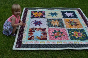Madeline pointing to all of the birds, flowers, and butterflies in the blanket.
